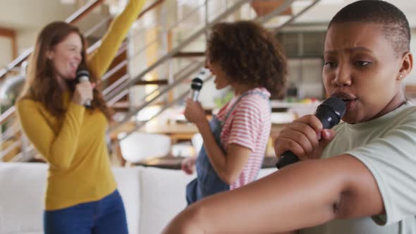 Diverse group of female friends having fun singing karaoke at home