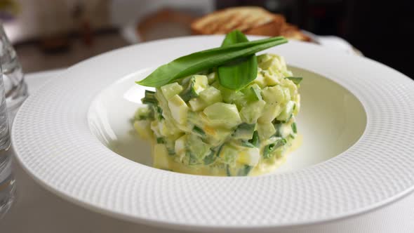 Salad of wild garlic, cucumber, boiled egg and sour cream rotates