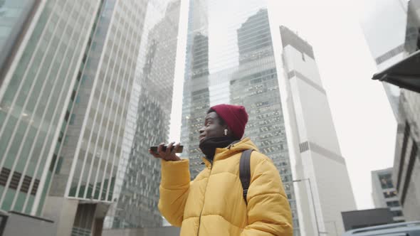 Young African Man Using Cellphone during Walk