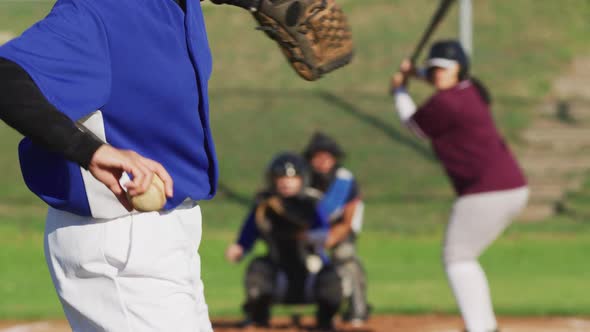 Diverse group of female baseball players in action on the field, pitched ball caught by catcher