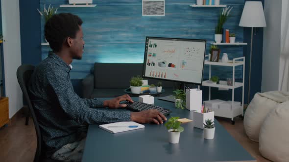 African American Guy Working From Home Taking Notes on Paper Notepad