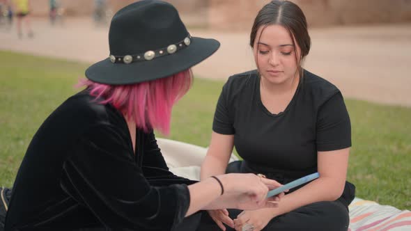 Brunette Girl Looks at Cellphone Screen Curious to What Her Friend Shows