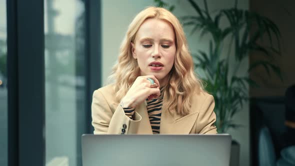 A beautiful woman works on a laptop, leads a zoom call in a cafe. Freelancer, businessman.