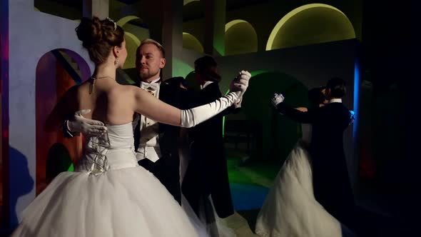 Elegant Gentlemen and Stunning Ladies are Dancing Waltz in Dark Ballroom Slow Motion Shot