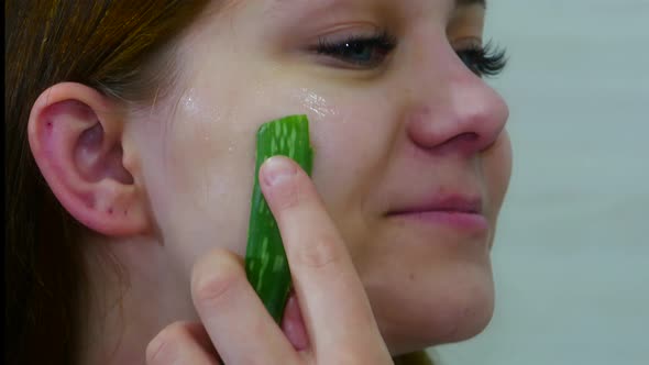 Portrait of Woman Looking in Mirror and Using Aloe Vera Leaf