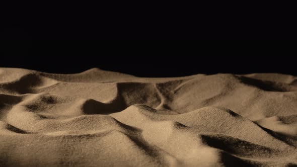 Camera Pans Over Mound of Dry Sand in Dark on Black Background
