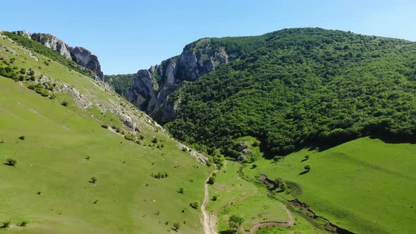 Wide aerial view as drone lifts off from an open green meadow to reveal the landscape beauty of Turd