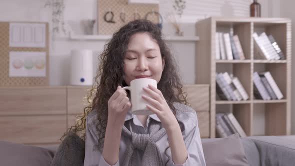 Asain woman sips coffee in the morning and wakes up with a white cup of coffee. Relaxing on weekends