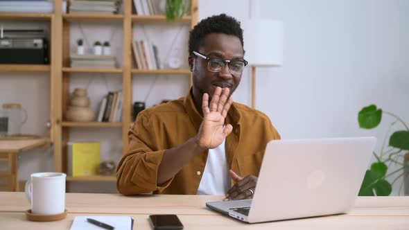 African Man with Glasses Waving Hand While Meeting Online on Laptop at Home Spbas