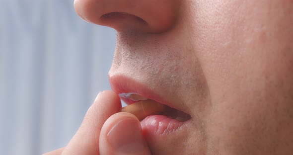 A Person Puts a Capsule in His Mouth