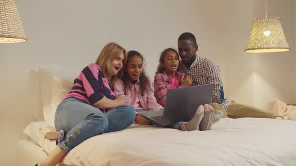Diverse Family Watching Scary Movie Online on Bed