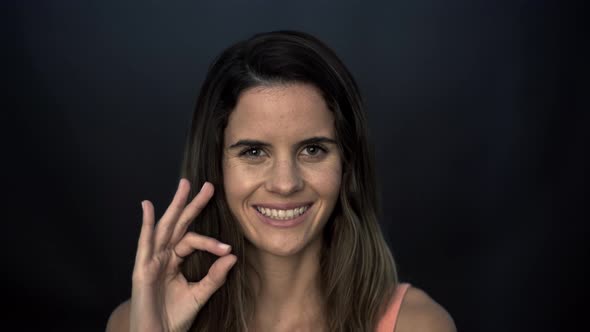 Woman giving ok sign and smiling cheerfully