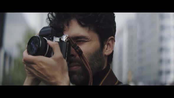 Caucasian man with beard taking pictures with vintage camera