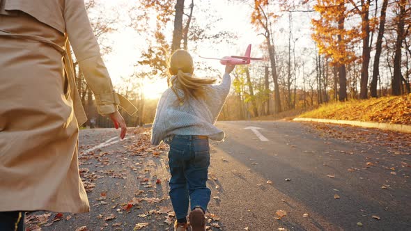 Unknown Parents Running with Little Daughter Launching Red Toy Plane