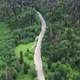 Drone footage of a driving car on the winding road through green forest and mountains pass - VideoHive Item for Sale