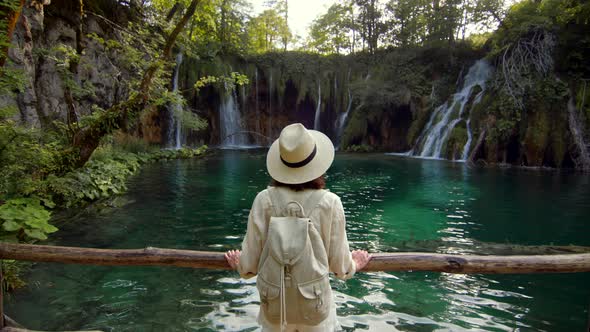 Young traveler on the wooden bridge near the waterfalls, slow motion