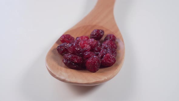 Red cranberry in a wooden spoon on a light gray table. 