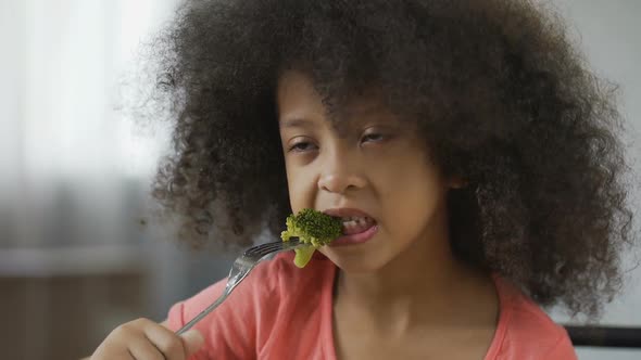 Funny African American Girl Eating Broccoli with Disgust, Healthy Food, Dieting