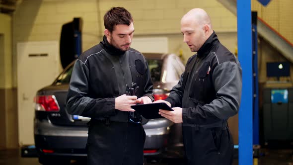 Auto Mechanics with Tablet Pc Talking at Car Shop