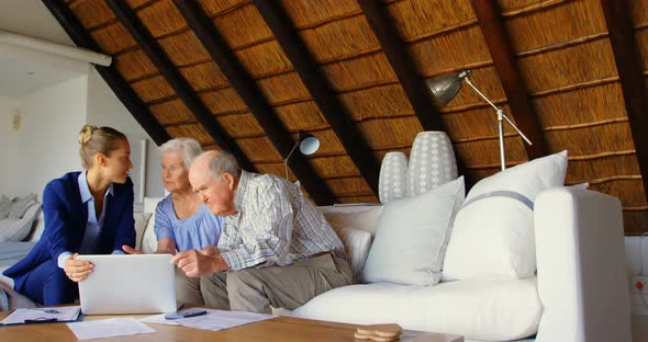 Front view of Caucasian senior couple discussing over clipboard with female doctor at comfortable co