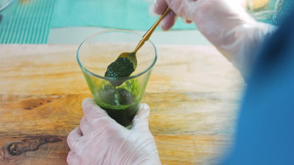 The Chef Mixes with a Golden Spoon the Chopped Spinach in a Transparent Glass