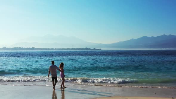 Man and lady tanning on paradise coastline beach voyage by aqua blue sea and white sand background o