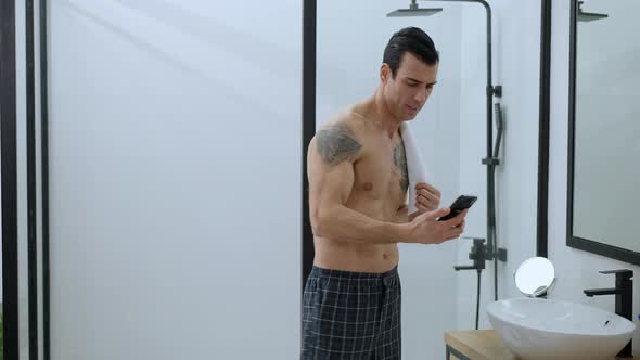 Portrait of Happy Handsome Man Receiving Message in Bathroom in the Morning