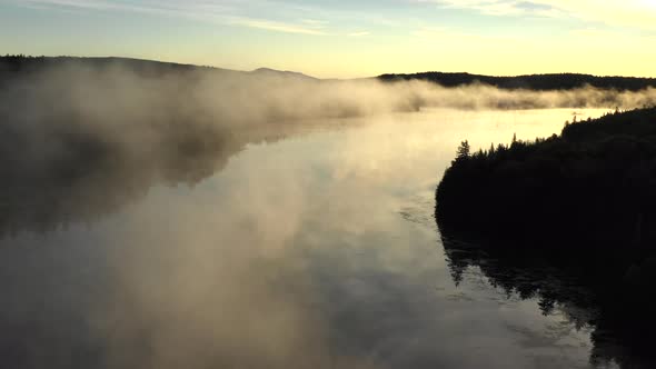 Aerial drone shot at sunset of the epic golden mist and calm waters of the Spectacle Ponds with the