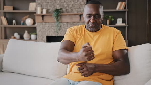 Mature Aged African American Man Mentor Coach Sits in Living Room Wears Yellow Tshirt Looking at