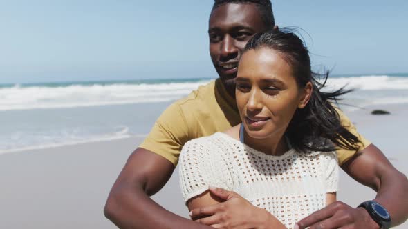 Happy african american couple hugging and embracing each other at the beach