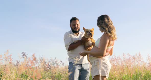 Couple playing with their pet dog, putting him on his pregnant belly to hear the little brother who