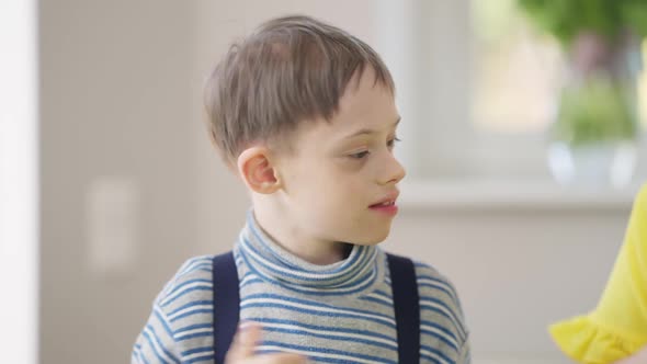 Front View Smiling Autistic Curios Boy Painting with Unrecognizable Woman Helping