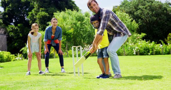 Family playing cricket in park