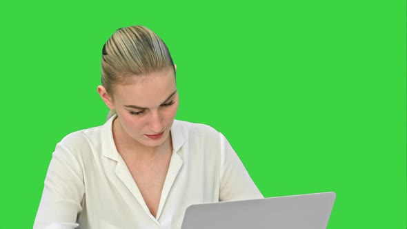 Young Blonde Businesswoman Working on Laptop Computer on a Green Screen, Chroma Key
