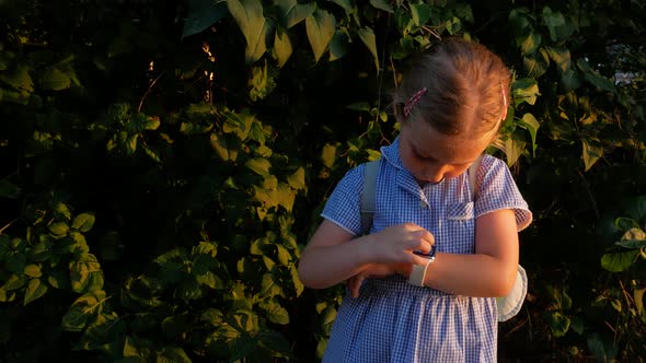 Kid using smartwatch outdoor in park. Child talking on vdeo call on the smartphone browsing internet alt