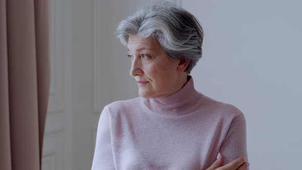 Beautiful Old Woman with Gray Hair Smiles Standing at Home