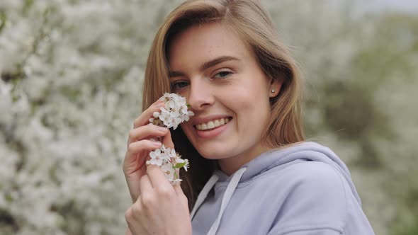 Positive Young Woman Posing with Flowering Branch in Park