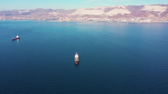 Aerial View Following the Ultra Large Cargo Ship at Sea Leaves Port at Sunset