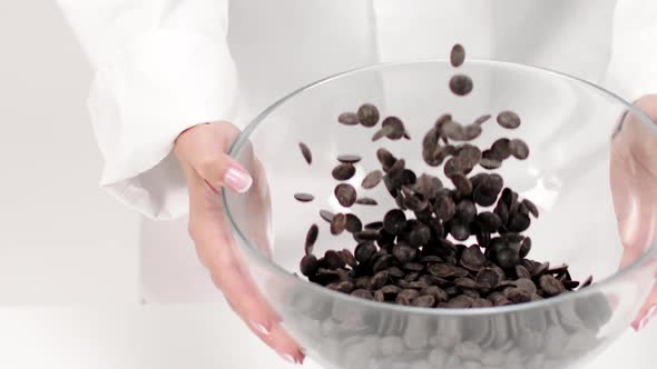 Closeup Chef Pours Dark Chocolate Chips on White Background, Slow Motion