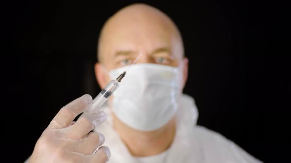 Close Up Doctor Hand in Protective Glove Holding Syringe with Injection Isolated on Black Background