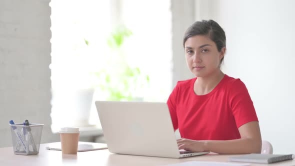 Indian Woman Smiling at Camera While Using Laptop in Office