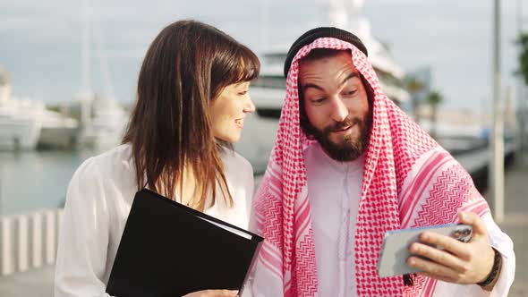 Smiling Arab Businessman Showing Something on Smartphone to His Attractive European Female Assistant