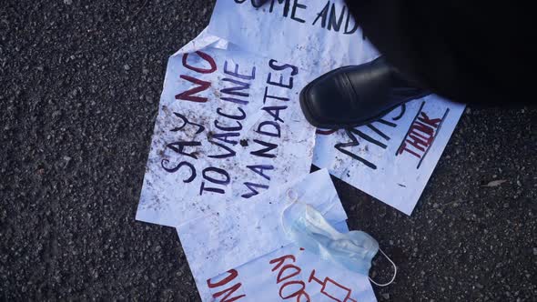 Top View Unrecognizable Woman Wiping Feet on Anti Vax Placards Scattered Outdoors
