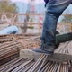 Close-up view of legs in foreground of a worker, cutting pipes with a saw blade. - VideoHive Item for Sale