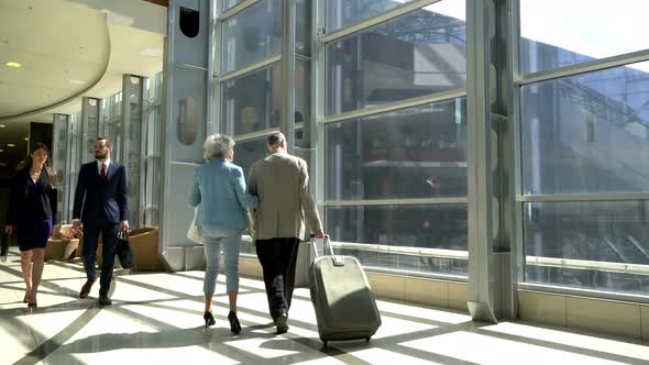 Two Seniors Walking with Suitcase