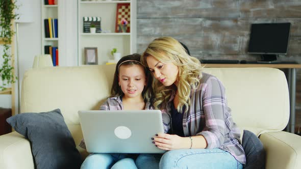 Little Girl and Her Mother Sitting on the Couch in Living Room