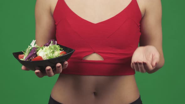 Cropped Shot of a Woman Choosing Between Salad and Vitamins in Pills