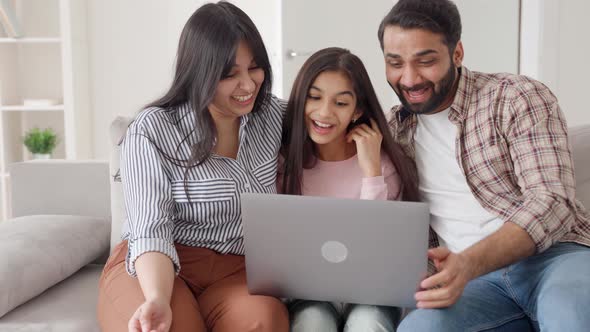 Laughing Family at Home in Living Room Using Laptop Watching Videos