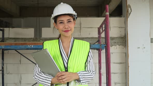 Portrait for Asian women engineer or Architect put on a helmet for safety and holding computer noteb