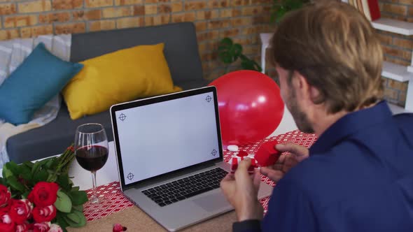 Rear view of caucasian man showing a ring on videocall at home